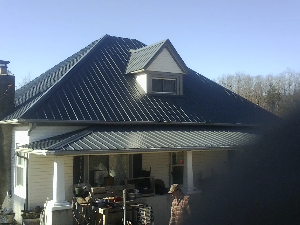 Dark blue standing seam metal roof with a dormer above a front porch in Ashby