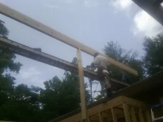 Carpenter setting a ridge beam over a new addition frame — Ice Dam Removal by Roofing Brothers in Ashby