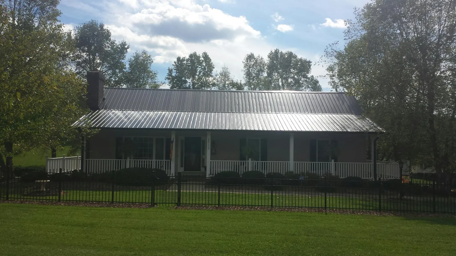 Gray metal roof on a brick ranch with a full width front porch — Gutter Guard Installation work by our crew in Ashby