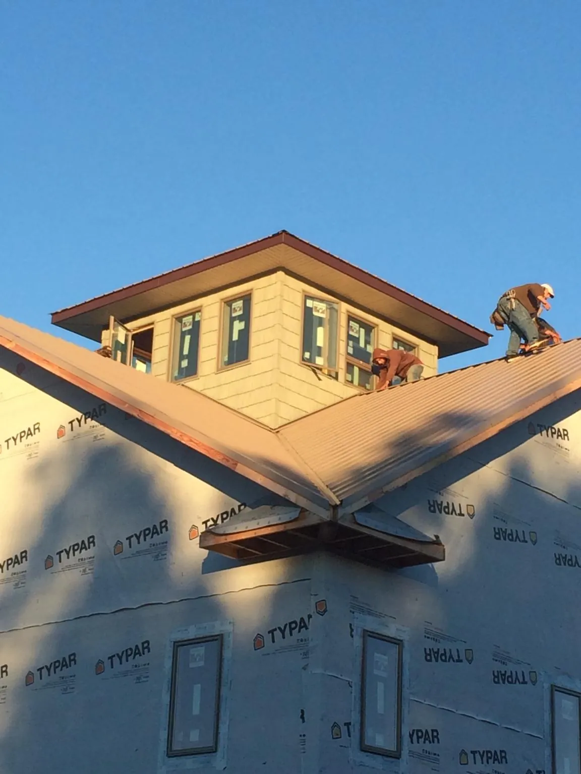 Roofers working around a rooftop cupola on a new metal roof at sunset — Roof Waterproofing in Ashby by Roofing Brothers